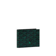 A Goyard bi-fold wallet featuring the brand's signature green and black chevron pattern, shown closed on a light cream background.