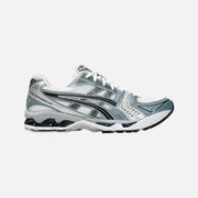 An Asics Gel-Kayano 14 running shoe in white and gray colors with a visible sole unit and lace-up closure.