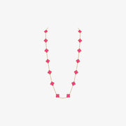 A delicate gold chain necklace featuring a series of bright pink clover-shaped beads, displayed against a clean, light gray background.